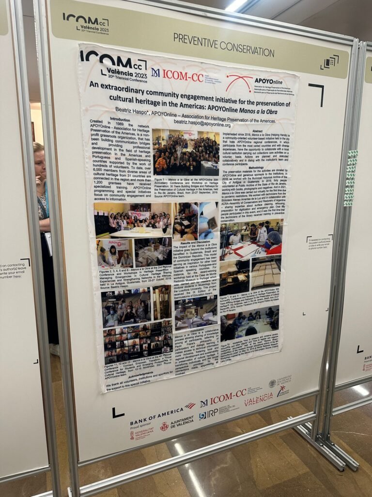 APOYOnline poster "An extraordinary community engagement initiative for the preservation of cultural heritage in the Americas: APOYOnline Manos a la Obra" hanging on the wall